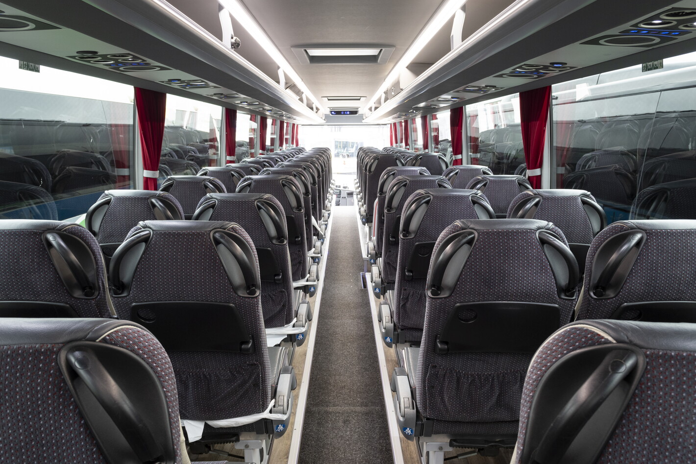 Lege stoelen in een moderne bus, gezien vanuit het middenpad richting de voorkant.