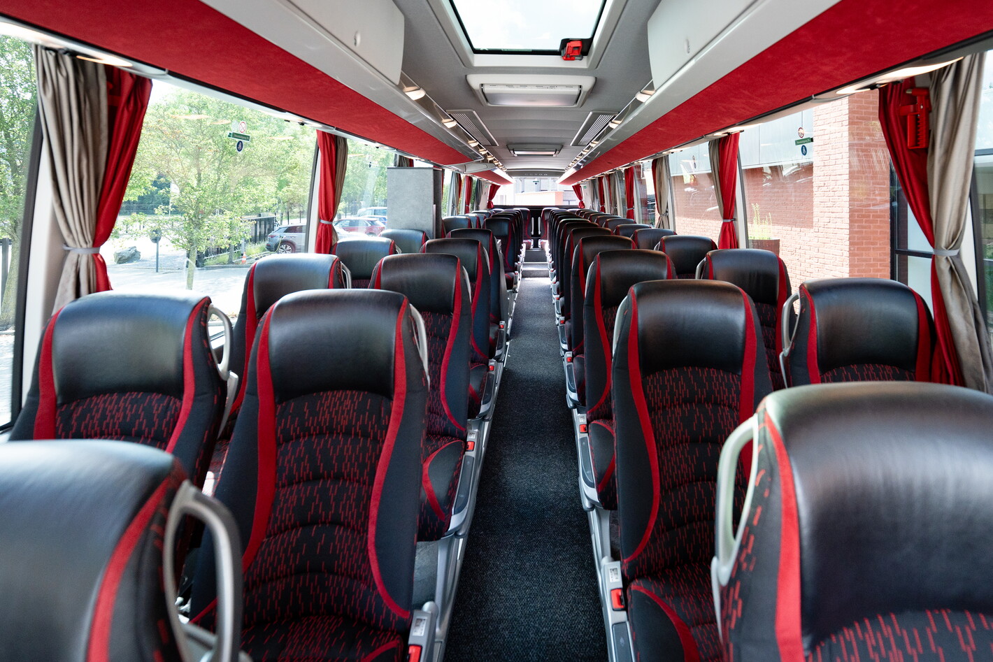 Lege bus met rijen zwart-rode stoelen en gangpad naar achteren