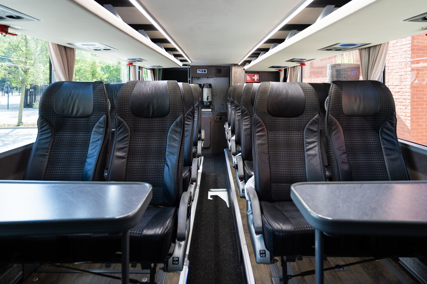 Lege leren stoelen met tafels in moderne treinwagon, uitzicht door ramen.