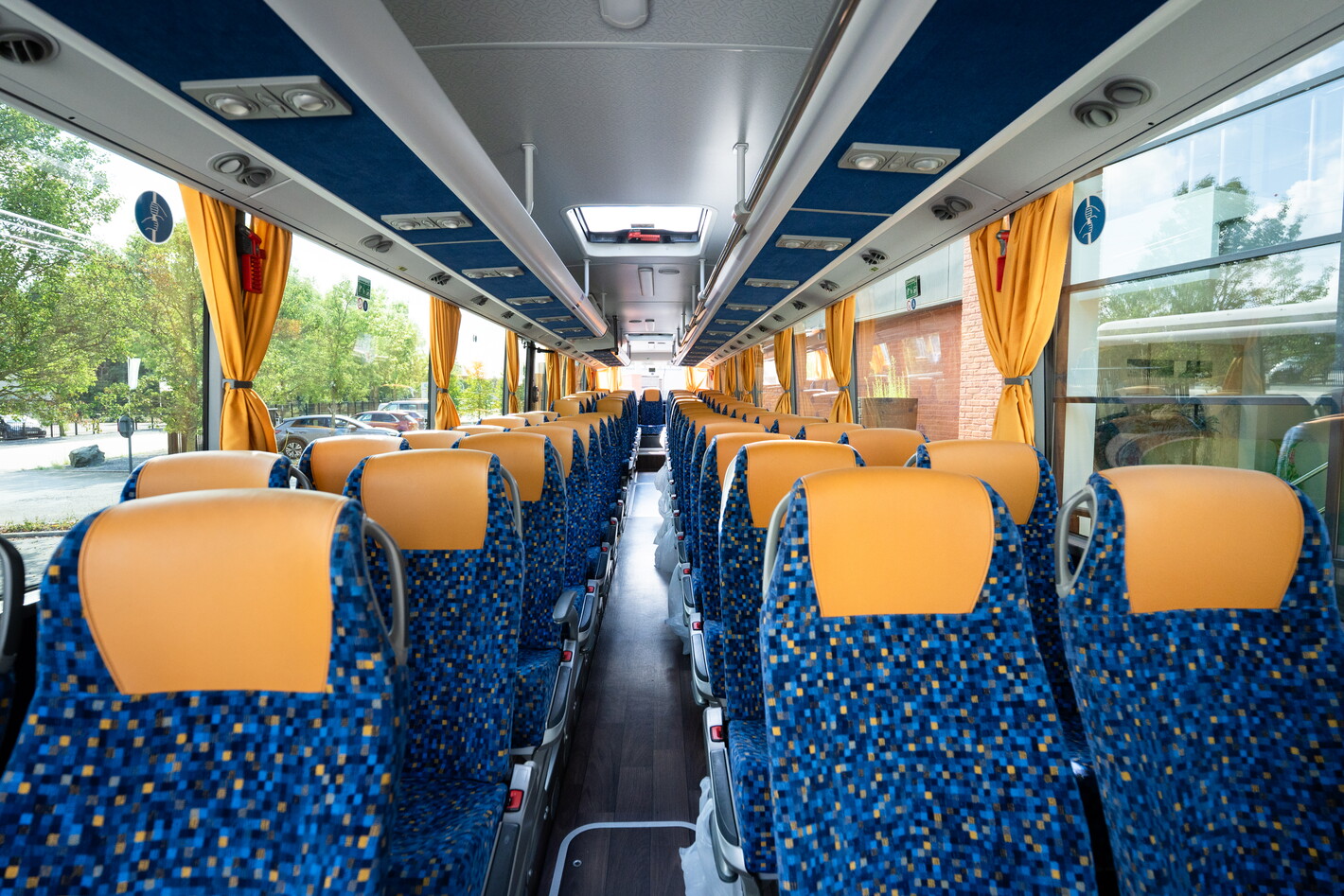 Interieur van touringcar met blauwe stoelen en oranje hoofdsteunen, leeg gangpad.