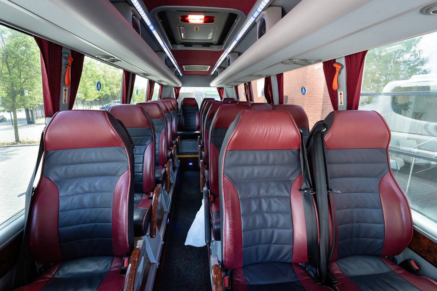 Interieur van touringcar met rood-zwarte leren stoelen en gangpad