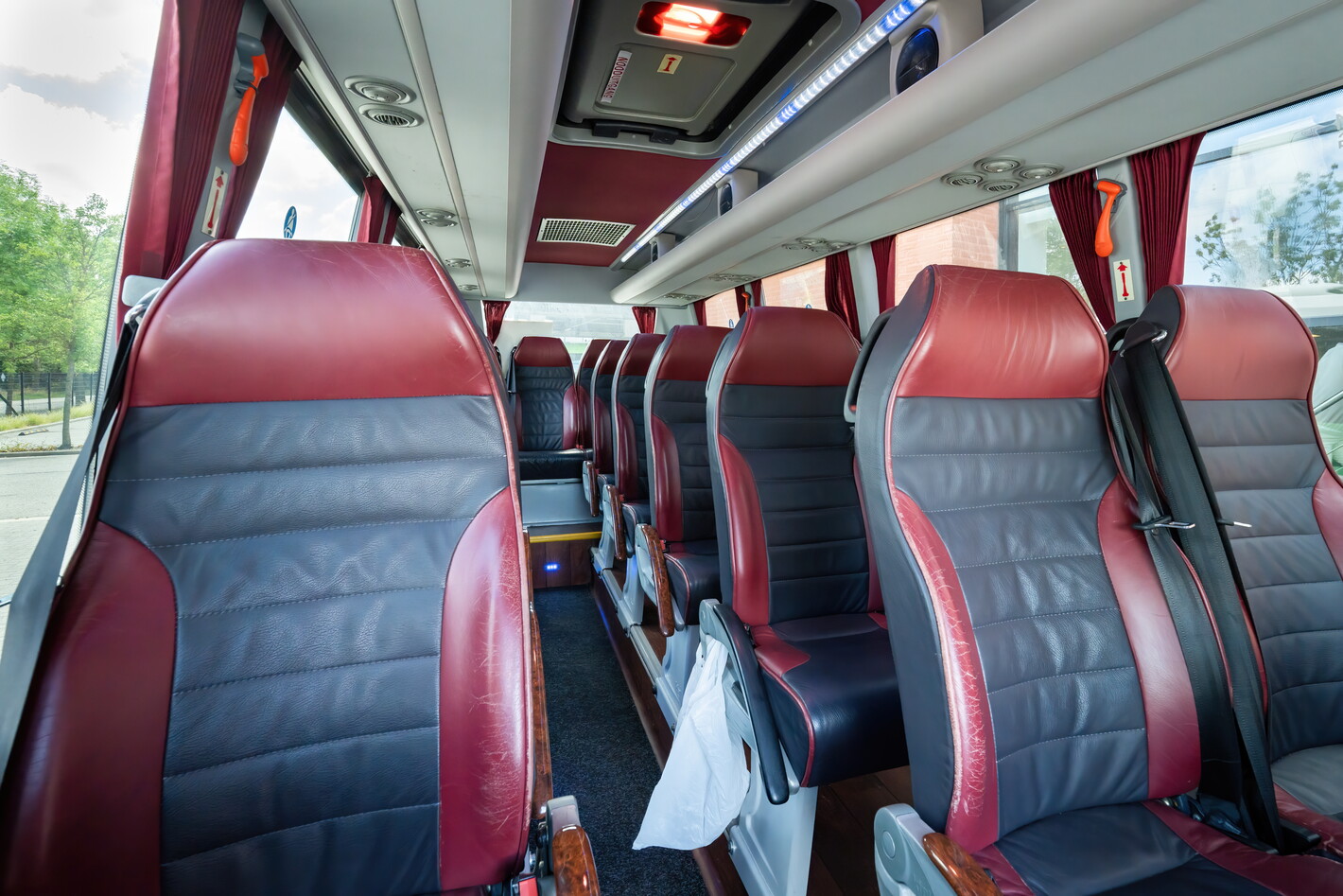 Lege busstoelen met rood‑grijze bekleding in een touringcarinterieur