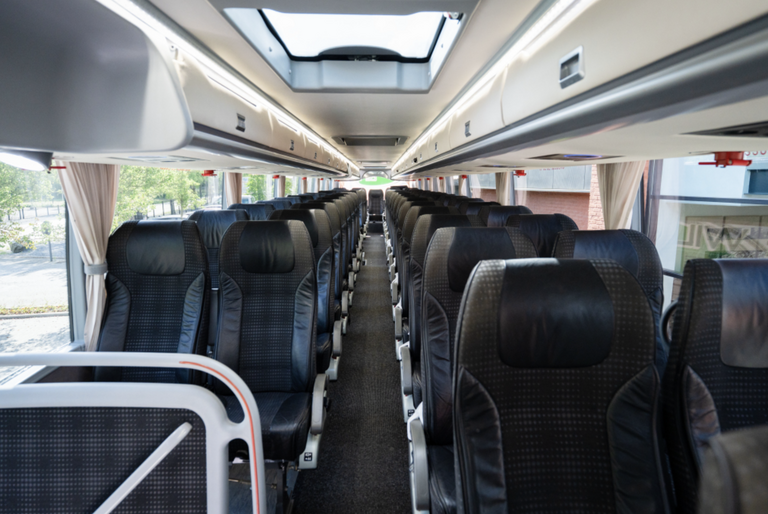 Interieur van touringcar met lege zwarte stoelen en middenpad onder dakraam